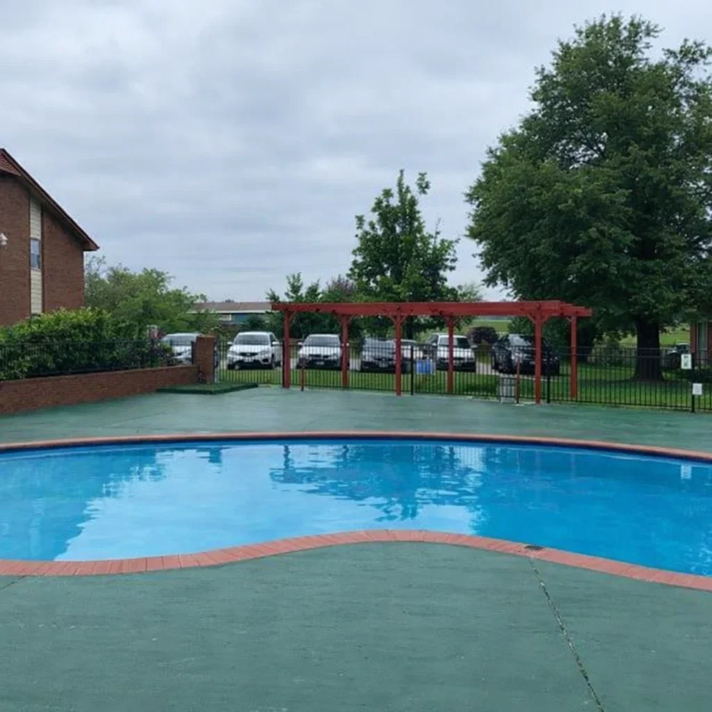 Community Amenities at La Villa Elms Outdoor swimming pool with brick trim and a red pergola at Oklahoma City apartments in El Reno.